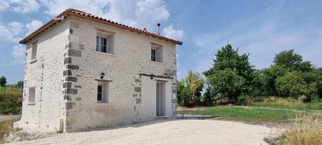 a small white brick building with a door at La Grange in Champagne-de-Blanzac