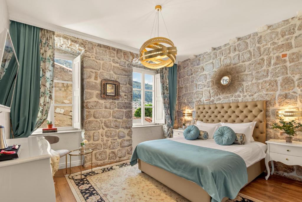 a bedroom with a large bed with a stone wall at Dominus Rooms in Dubrovnik
