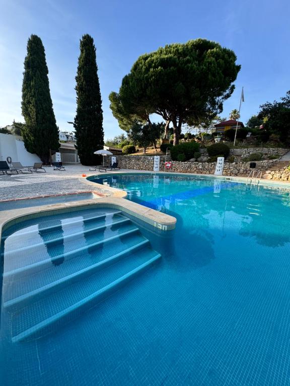 a large swimming pool with blue water and trees at Casa Gatu Verdi-Garden Apartment with Pool in Carvoeiro