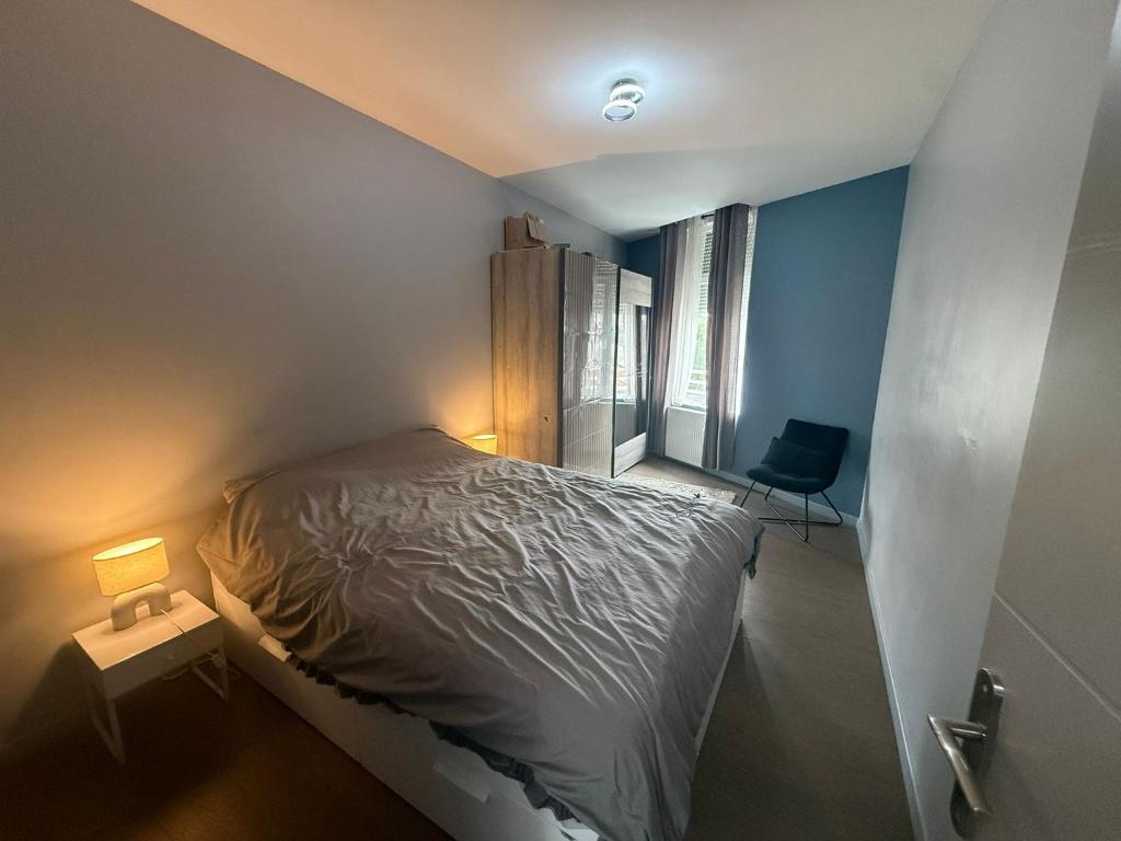 a small bedroom with a bed and a chair at Appartement Cuvier in Roubaix