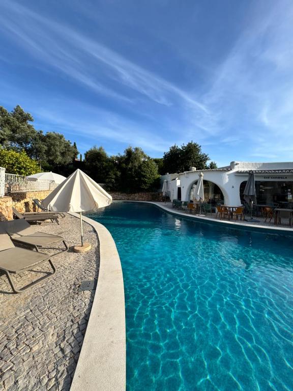 a swimming pool with chairs and an umbrella at Villa Valentina-Sunny 2 Bedroom House with Pool in Carvoeiro