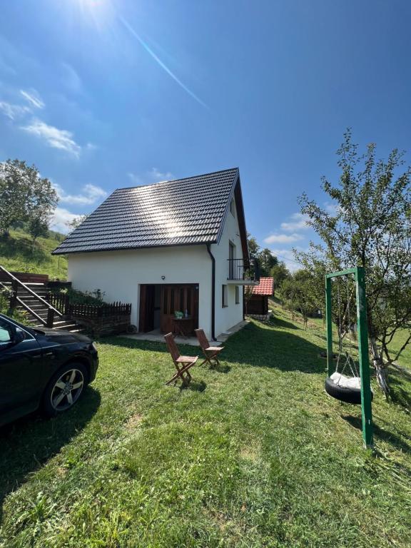 a small white house with a car parked in the yard at Peaceful Cottage in Bijelo Polje