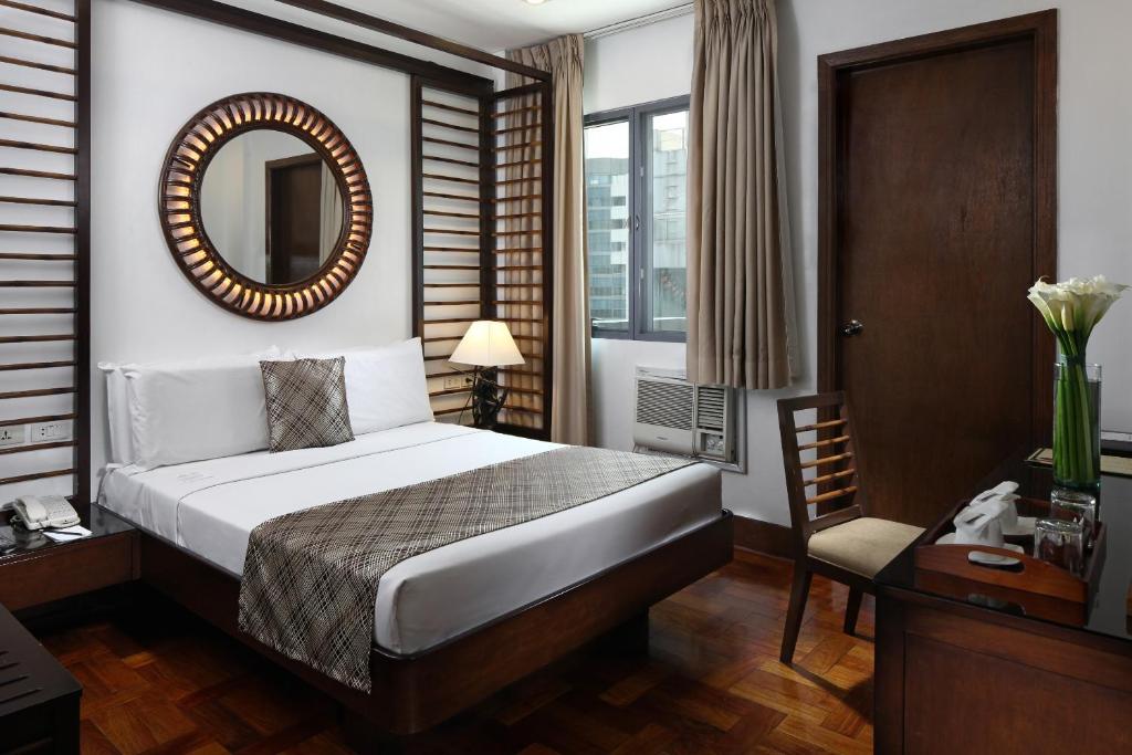Manila Lotus Hotel في مانيلا: غرفة نوم بسرير ومرآة وكرسي