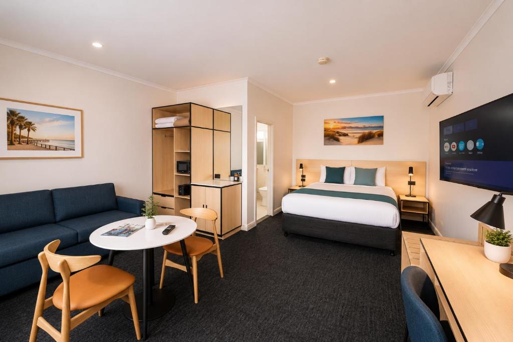 a hotel room with a bed and a couch at Glenelg Motel in Adelaide