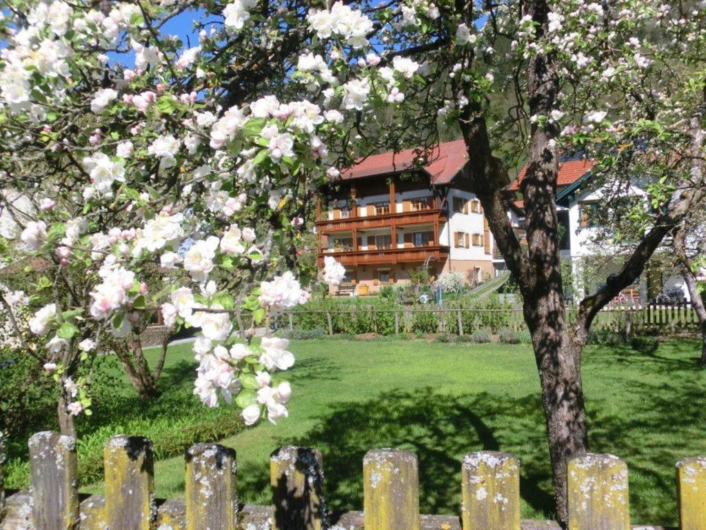 einen Zaun vor einem Haus mit einem blühenden Baum in der Unterkunft Gästehaus Struggl in Steindorf am Ossiacher See