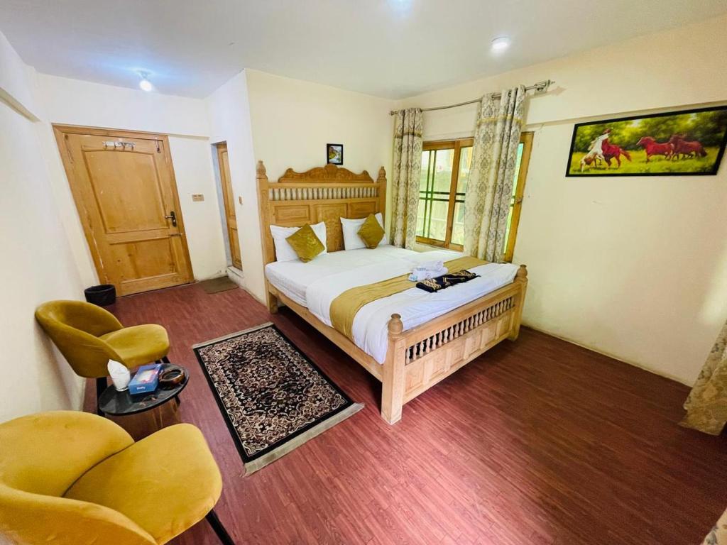 a bedroom with a bed and two chairs in it at IBEX COTTAGE SHARDa in Shardi