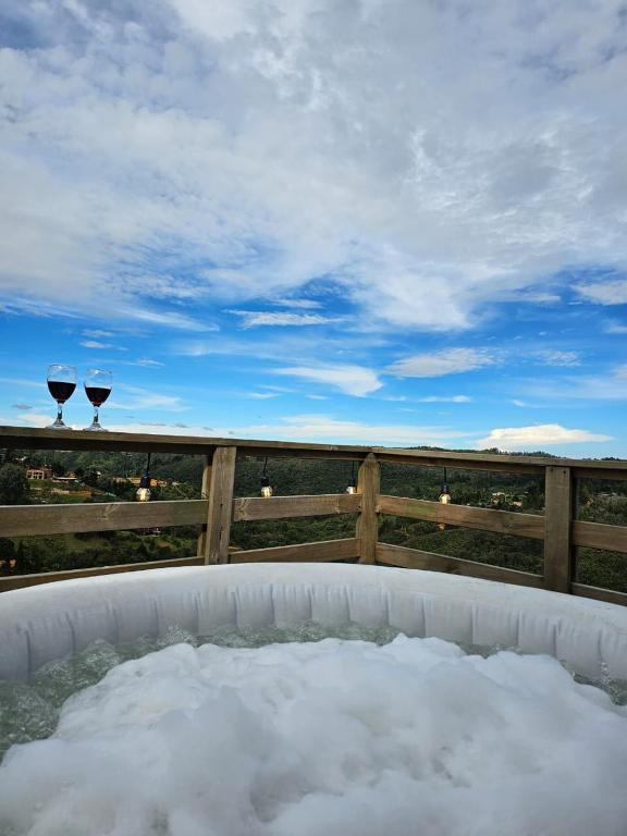 a hot tub with two wine glasses on a fence at cabaña sol in Santa Elena