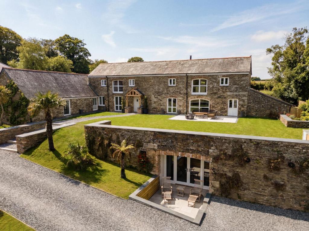 an exterior view of a large stone house with a yard at Treloggas Retreat in Truro