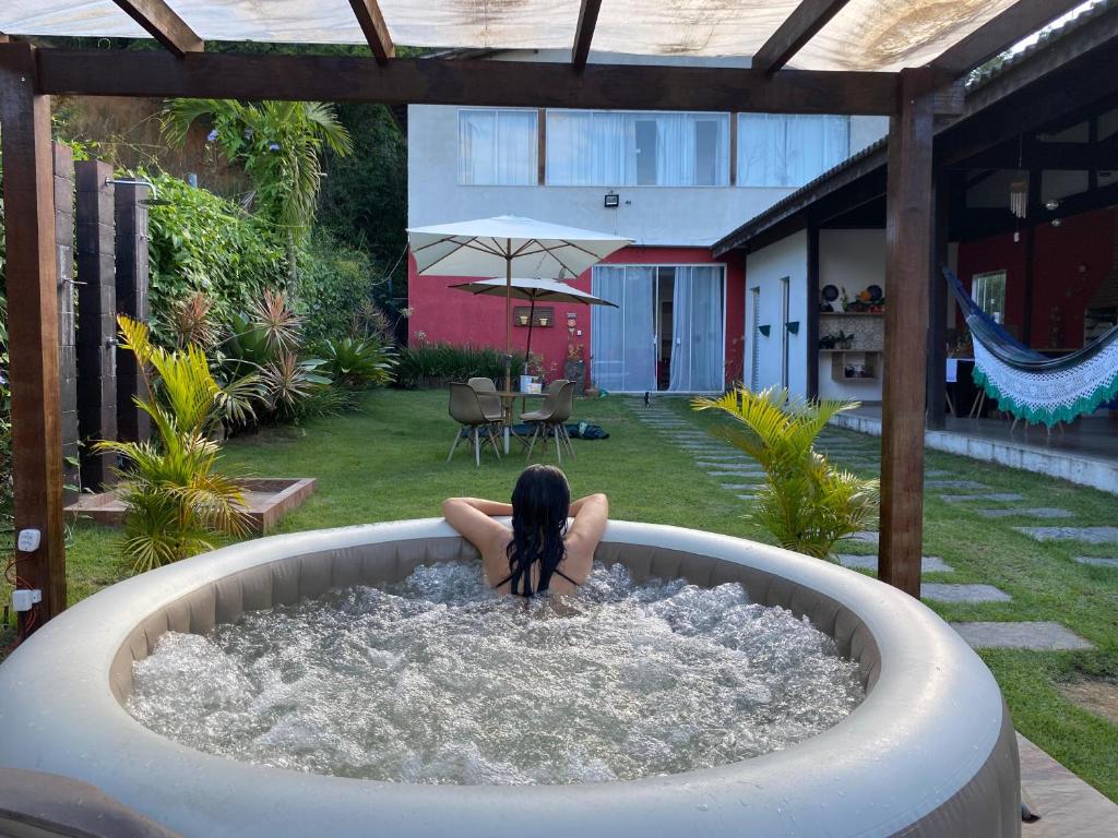 a woman sitting in a hot tub in a backyard at Yeshua - Casa da Claudia 8 in Ilha de Guaratiba