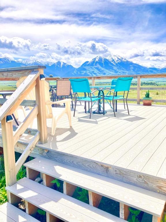 a deck with chairs and tables with mountains in the background at Near Yellowstone Park and Chico Hot Springs in Emigrant