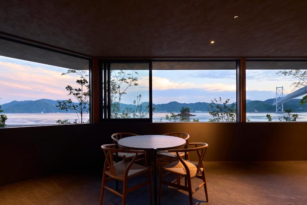 a table and two chairs in a room with windows at Seaside Villa SEEN Shallow Sea in Onomichi
