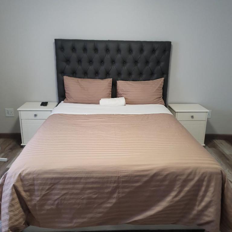 a large bed with a black headboard and two night stands at Khomasdal B&B in Windhoek