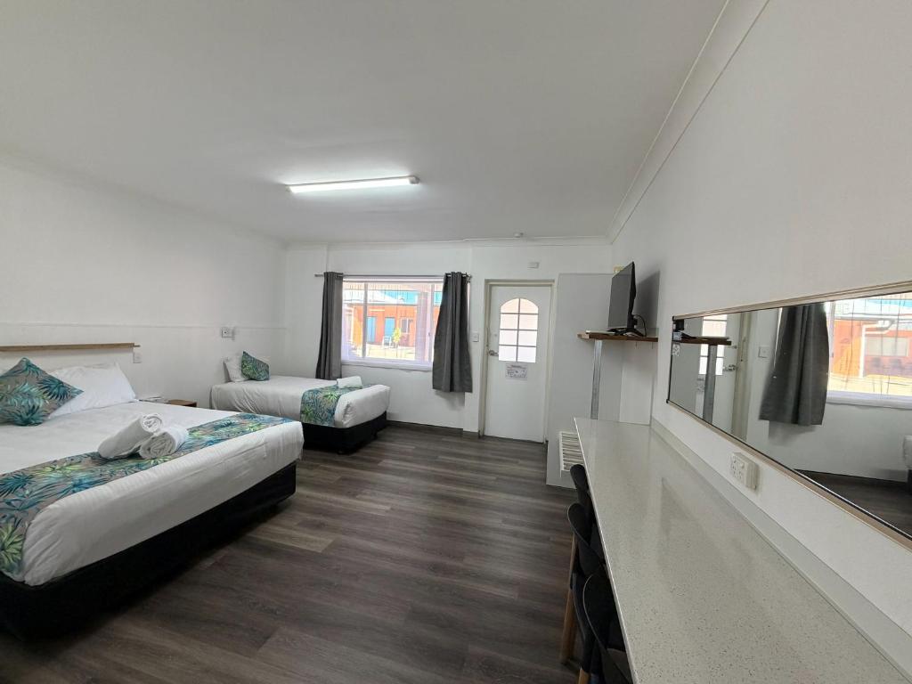 a hotel room with two beds and a television at Riviera Motel Bundaberg in Bundaberg