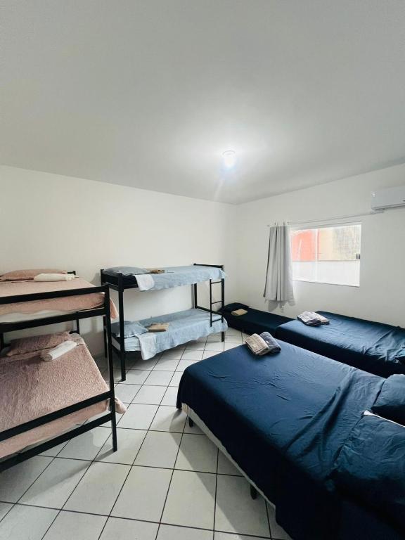 a room with two beds and a table and a desk at Suíte com ampla área externa - Pink in São Luís
