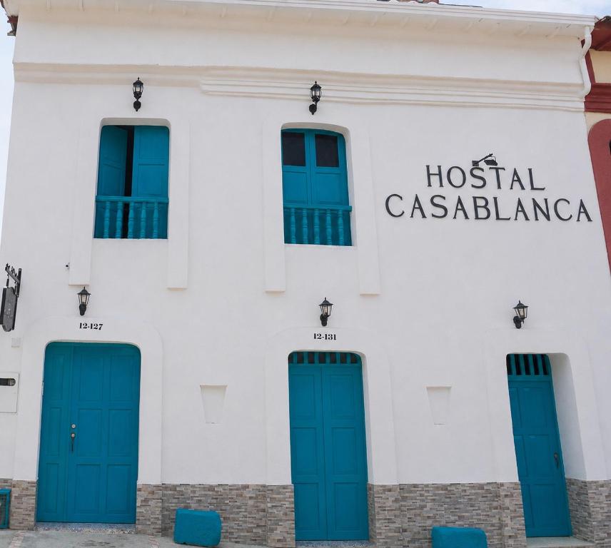 a white building with blue doors and a hospitalacienda at Hostal Casablanca in San Gil