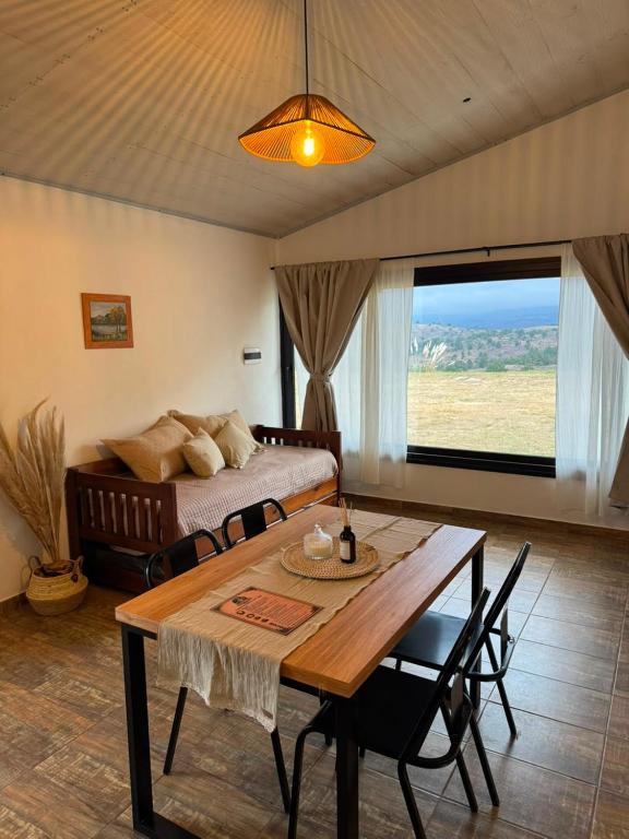 a living room with a bed and a wooden table at Crisálida Cabañas Villa Yacanto in Villa Yacanto