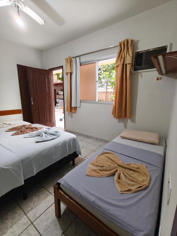 two beds in a room with a window at Pousada Ilha do sol in Piúma