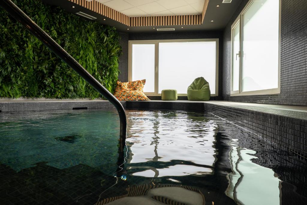 a swimming pool in a room with a swimming pool at Hotel Libera Spa et Restaurant Caen Colombelles in Caen