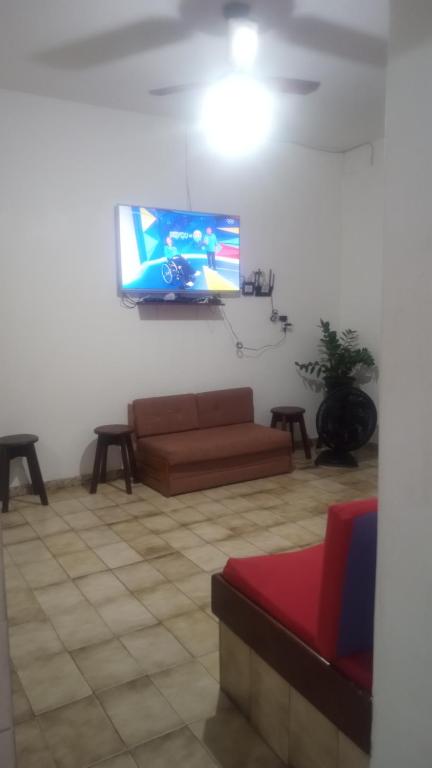 a living room with a couch and a flat screen tv at Aconchegante casa piuma in Piúma