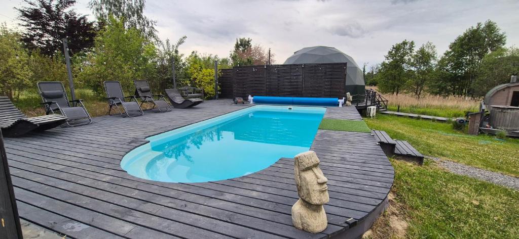 a swimming pool on a wooden deck next to a building at Kopuła glampingowa Boho in Krzesimów