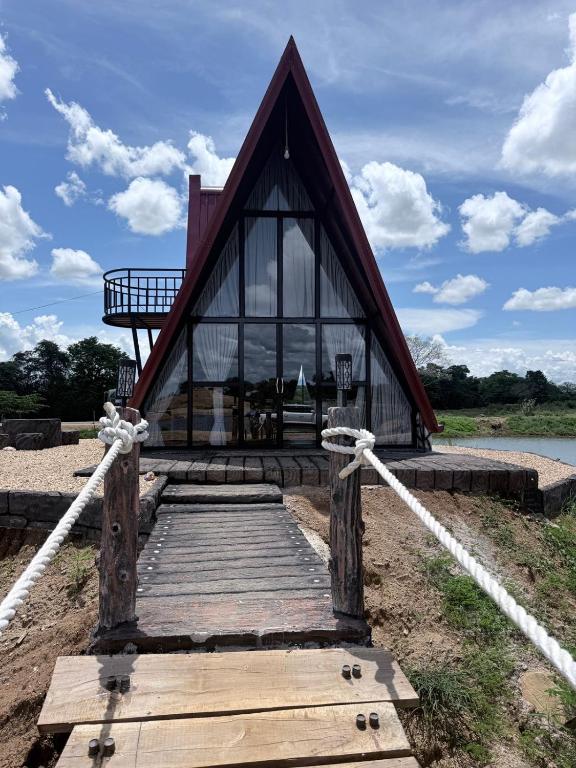 a wooden bridge leading to a house with a roof at Nelli Kale Holiday Resort in Huratgamuwa