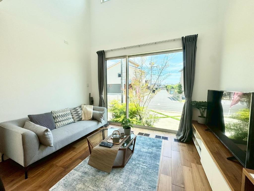 a living room with a couch and a tv at Akikawa Koshi 1 プレミアム鉄骨 一棟貸切ヴィラ in Yuge