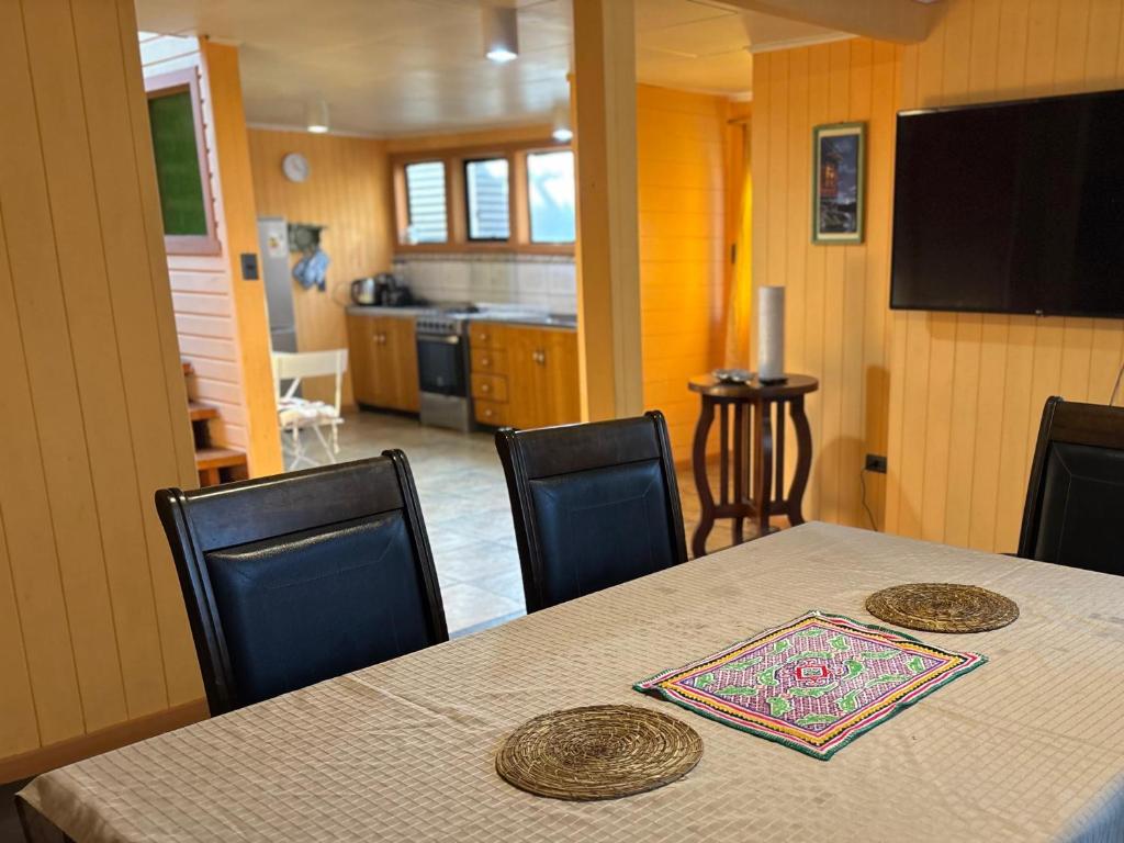 a dining room table with chairs and a kitchen at Casa Mañío Hostal Castro in Castro