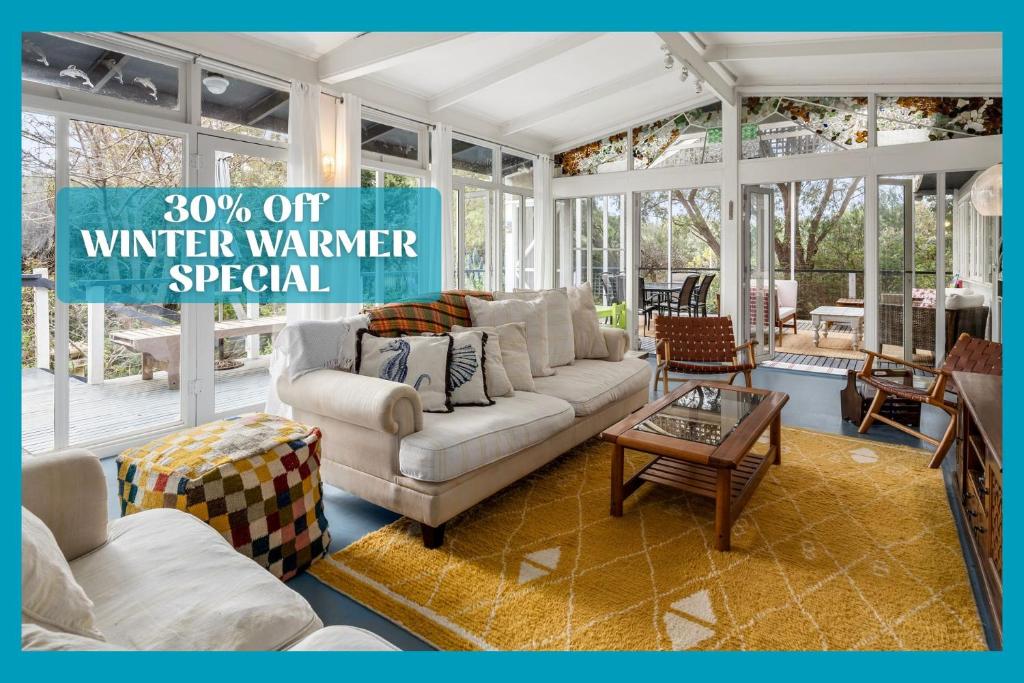 a living room with white furniture and a sign that reads winter warmer special at Seaside Sanctuary in Saint Leonards