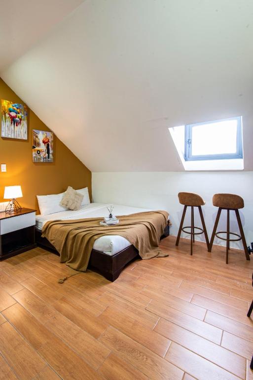 a bedroom with a bed and two stools in it at The Node Homestay & Apartment in Xuan An