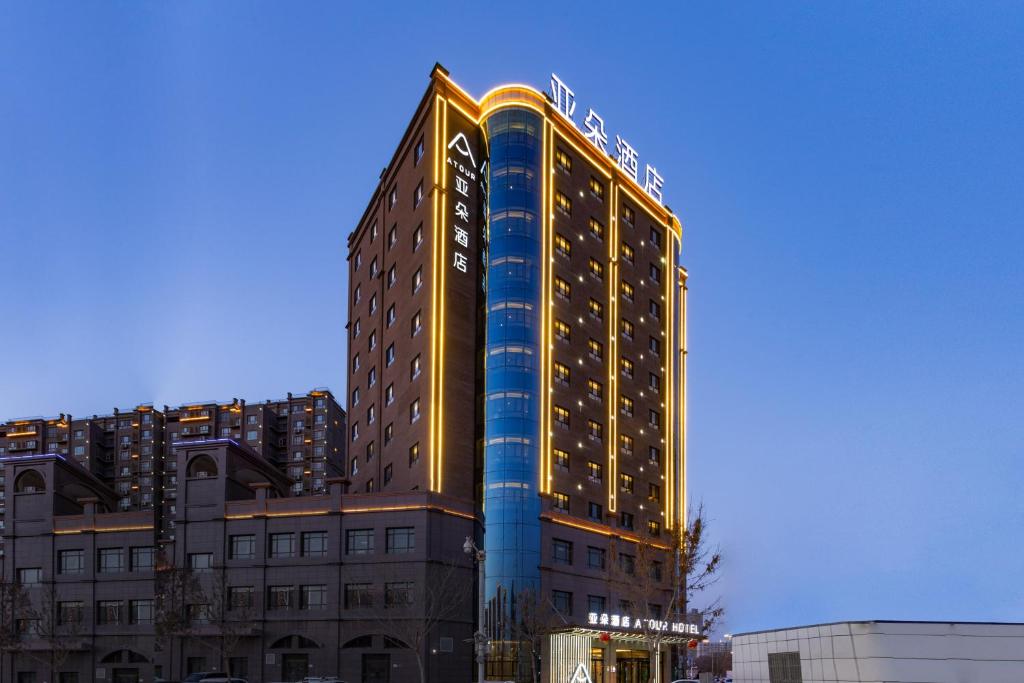a tall building with a sign on the side of it at 库尔勒孔雀河景观带滨河西路亚朵酒店 in Korla