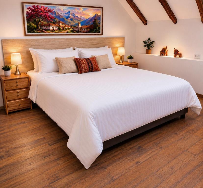 a large white bed in a room with wooden floors at Loft Casa Yucay in Yucay