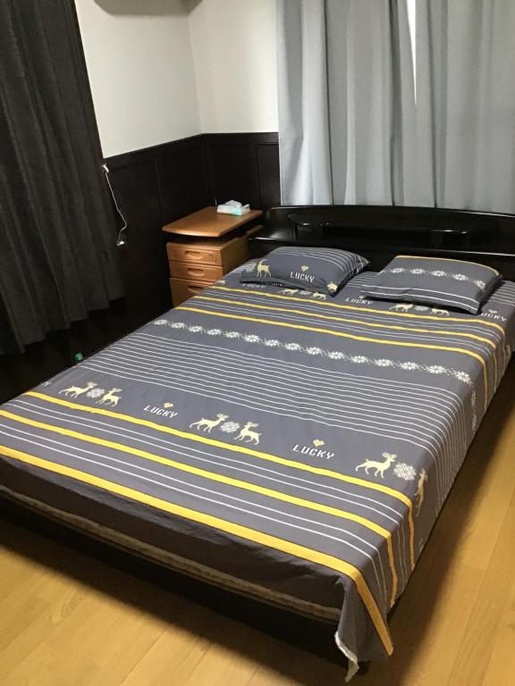 a bed with blue and yellow striped sheets in a bedroom at 安易 旅館1号房间 in Okayama