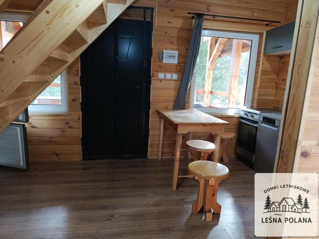 a kitchen in a log cabin with a table and stool at Leśna Polana in Zbiczno
