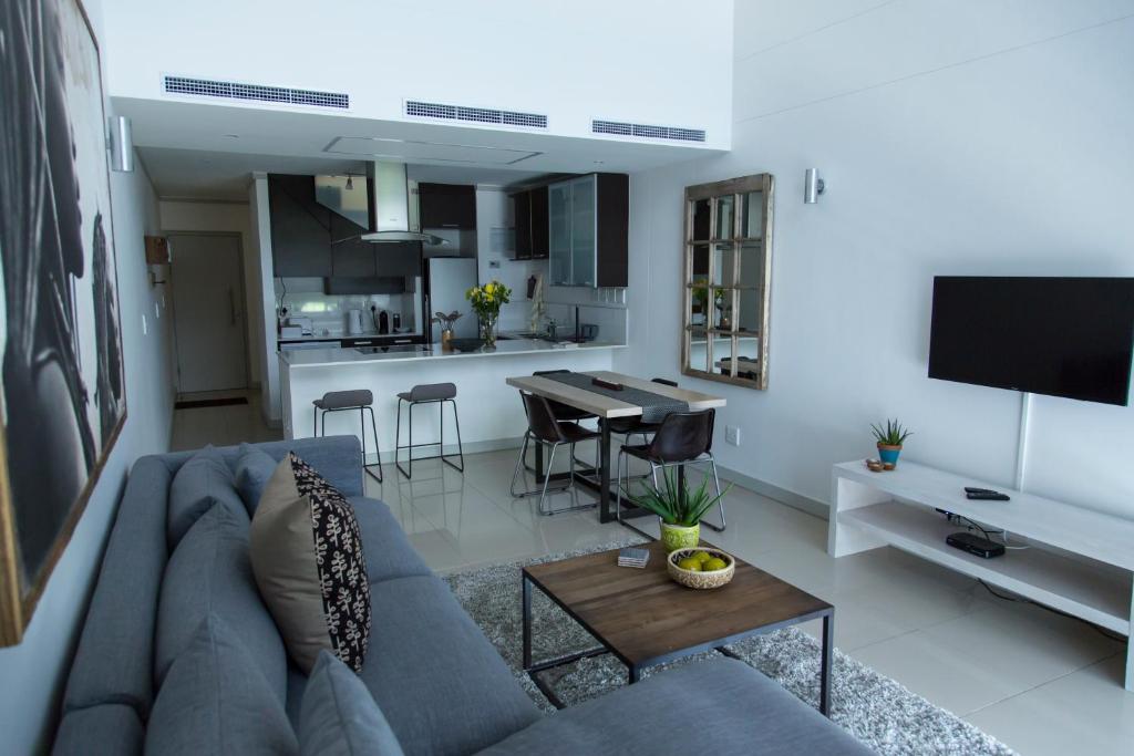 uma sala de estar com um sofá azul e uma cozinha em The Quadrant Apartment A406 na Cidade do Cabo