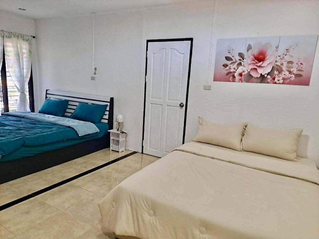 a white bedroom with a bed and a painting on the wall at Pani House Hatyai 6 in Hat Yai