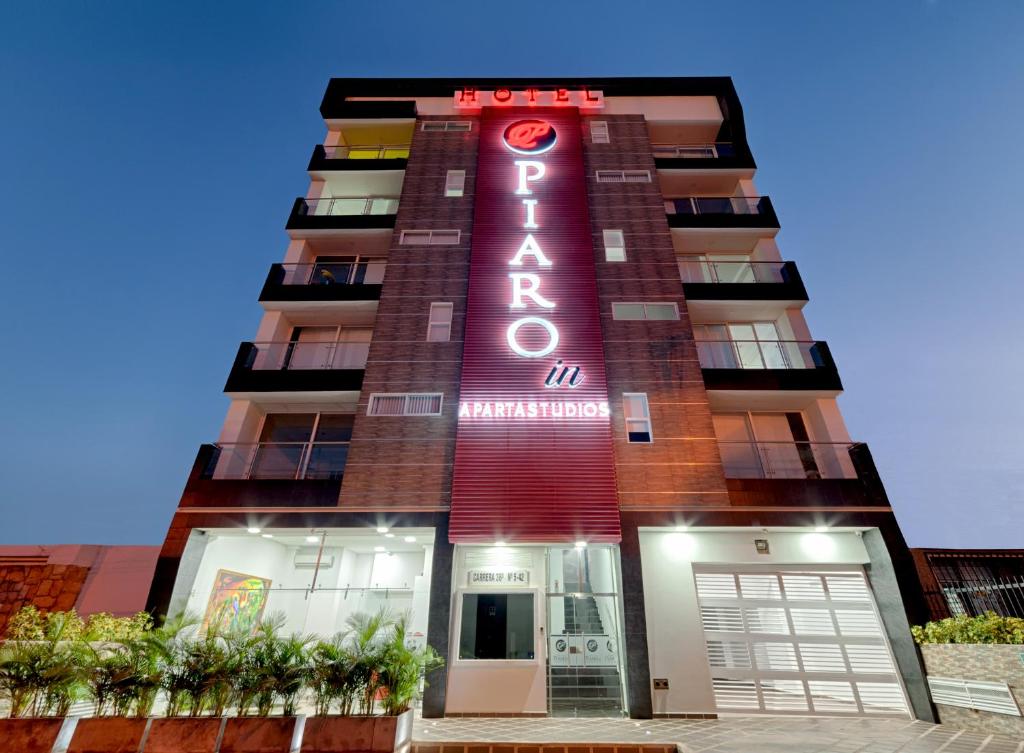 a tall building with a red neon sign on it at Hotel Piaro In Suites in Cali