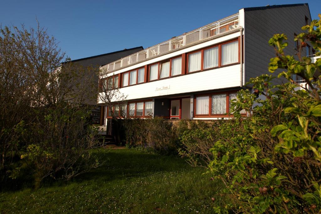 ein weißes Gebäude mit roten Fenstern und einem Hof in der Unterkunft Haus Rooad Weeter in Helgoland