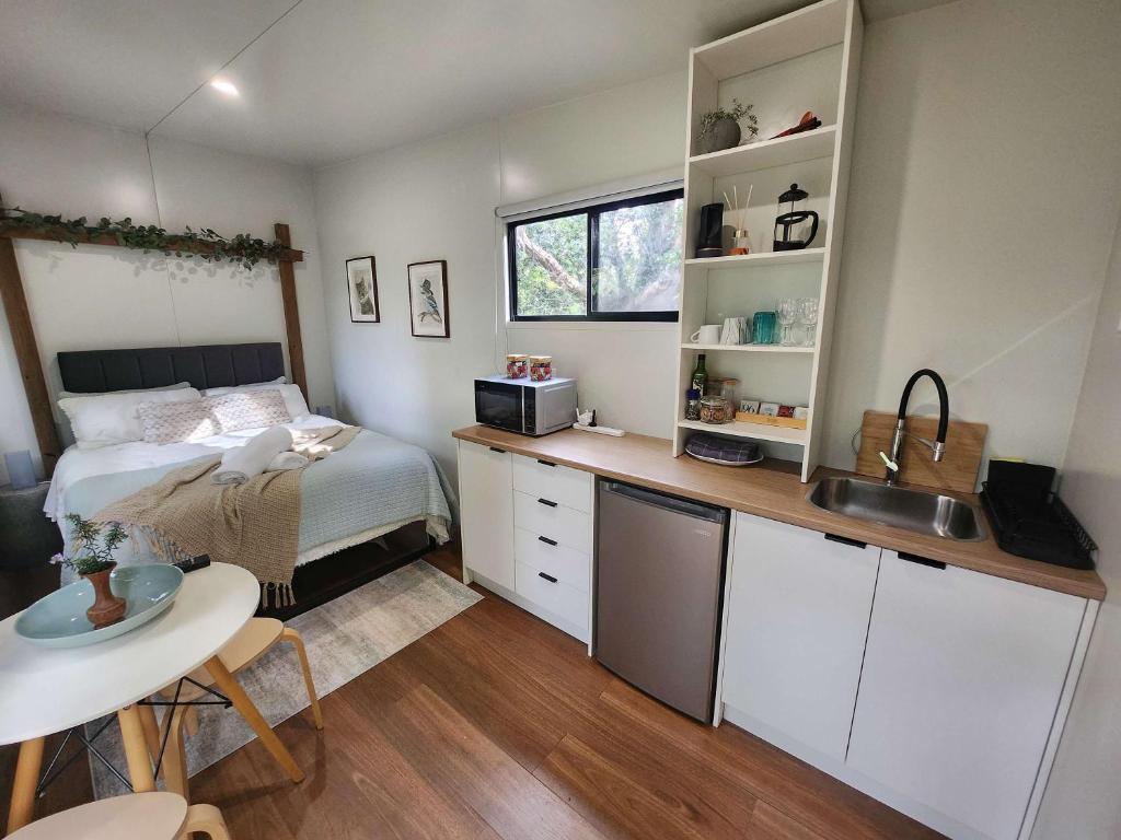 a bedroom with a bed and a kitchen with a sink at Rosebank Tiny House in Healesville