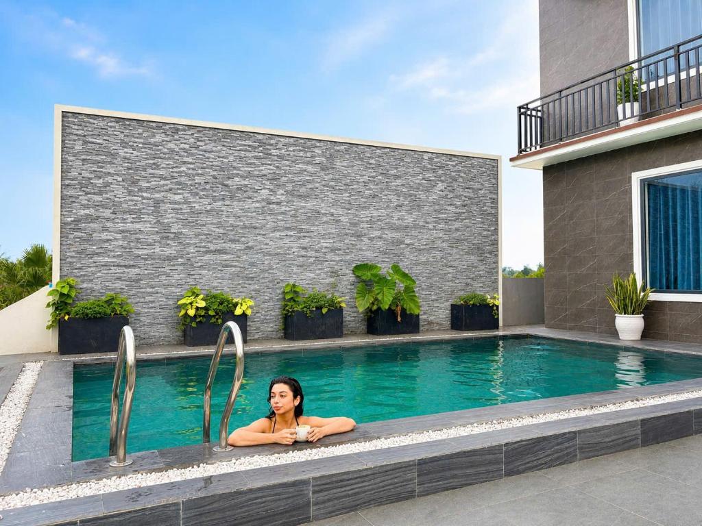 a woman laying in a swimming pool next to a building at TuTu's Homestay Phong Nha in Phong Nha