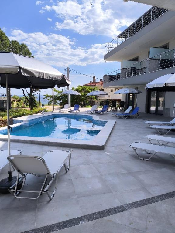 a swimming pool with chairs and umbrellas next to a building at Garden and Sea in Nikiti