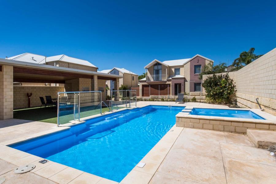 a swimming pool in front of a house at Serenity Townhouse in Mandurah