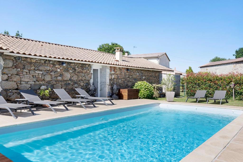 a swimming pool with chairs and a house at Aux Charmes D'antan - Chambre in Sevremont