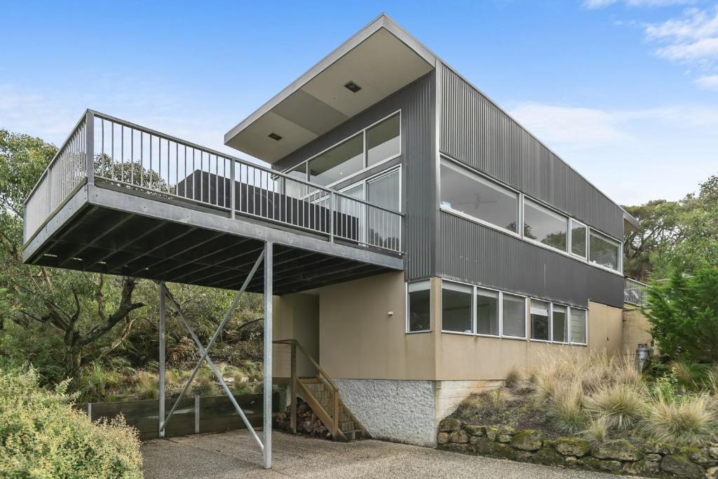 a large black house with a balcony on a hill at Timbara Hideaway - Ocean Views - Pet Friendly in Moggs Creek
