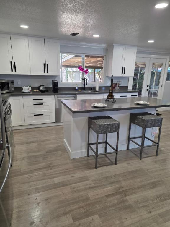 a kitchen with white cabinets and a large island with stools at Cozy SeaTac home in SeaTac