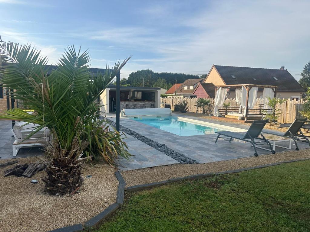 a swimming pool with two chairs next to a house at La Villa cocooning in Changé