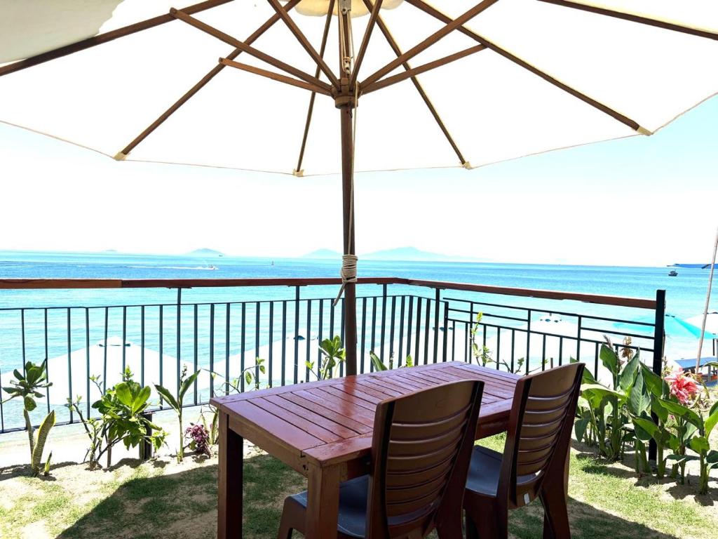 a wooden table with chairs and an umbrella on a balcony at Hidden Beach Bungalow Sea View in Hoi An