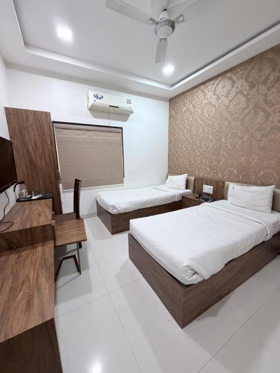 a hotel room with two beds and a desk at Hotel SR Executive, Akola in Akola