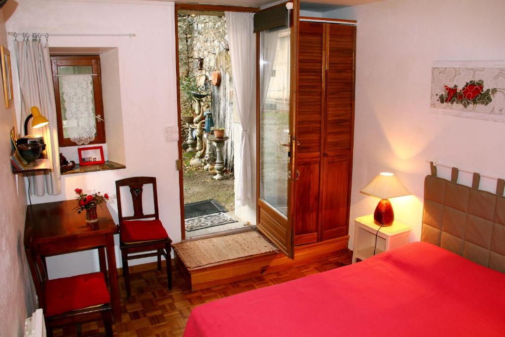 een slaapkamer met een bed, een raam en een bureau bij Chambre d'Hôtes la Poterie in Caunes-Minervois