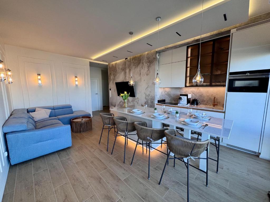 a living room with a blue couch and a kitchen at Aqua Concept Apartment Sol Marina in Wiślinka