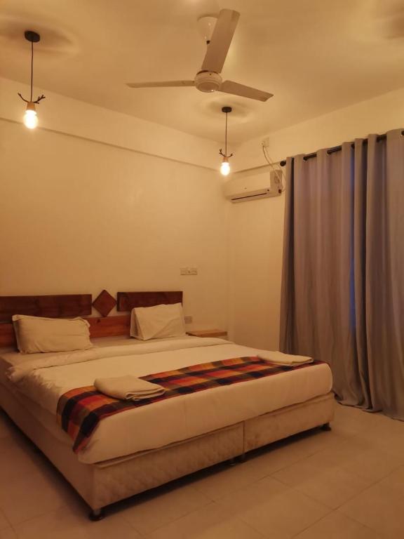 a bedroom with a large bed with a ceiling fan at Banana villa in Rasdhoo